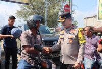 Kapolres Pidie Jaya AKBP Ahmad Faisal Pasaribu, S.H., S.I.K., M.H., membagikan helm gratis kepada pengendara sepeda motor di Simpang Layang Lampu Merah Meureudu, Selasa (11/2) Foto.Ist